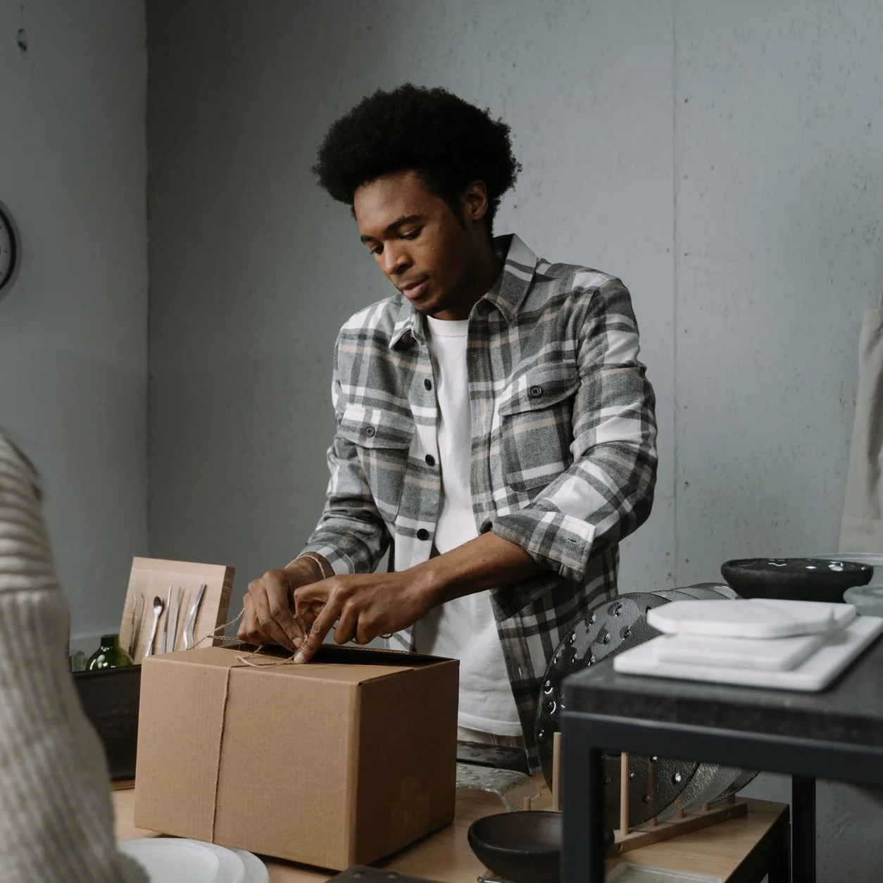 A man carefully packs a box in a retail setting, preparing goods for a customer.