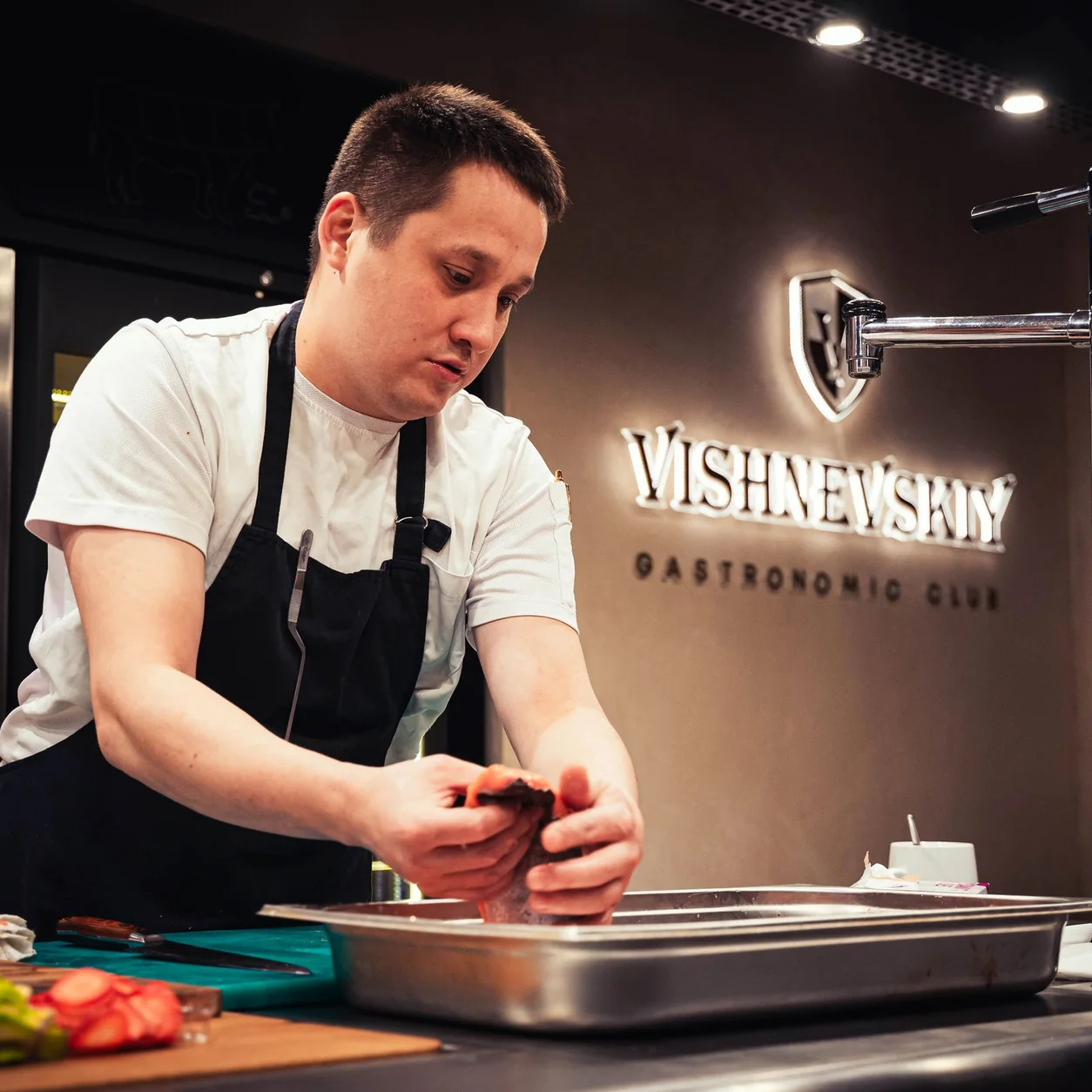 A chef preparing food at a professional restaurant worktop.