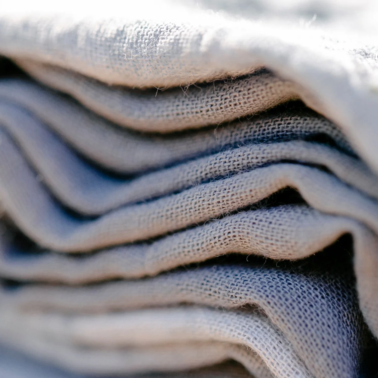 Folded natural linens in warm sunlight.