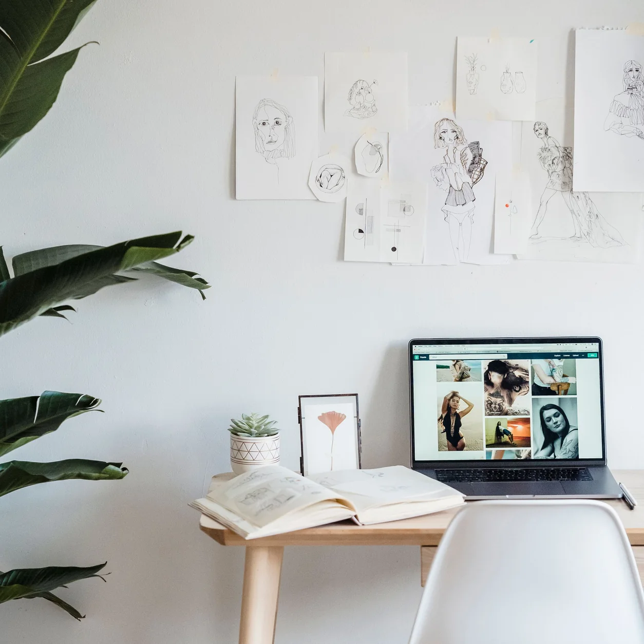 A sunlit creative workspace with a laptop and open sketchbook.