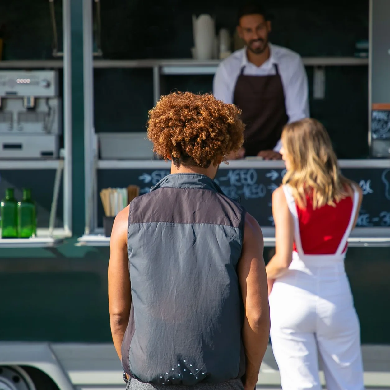 Customers choosing an order at a food truck service window.