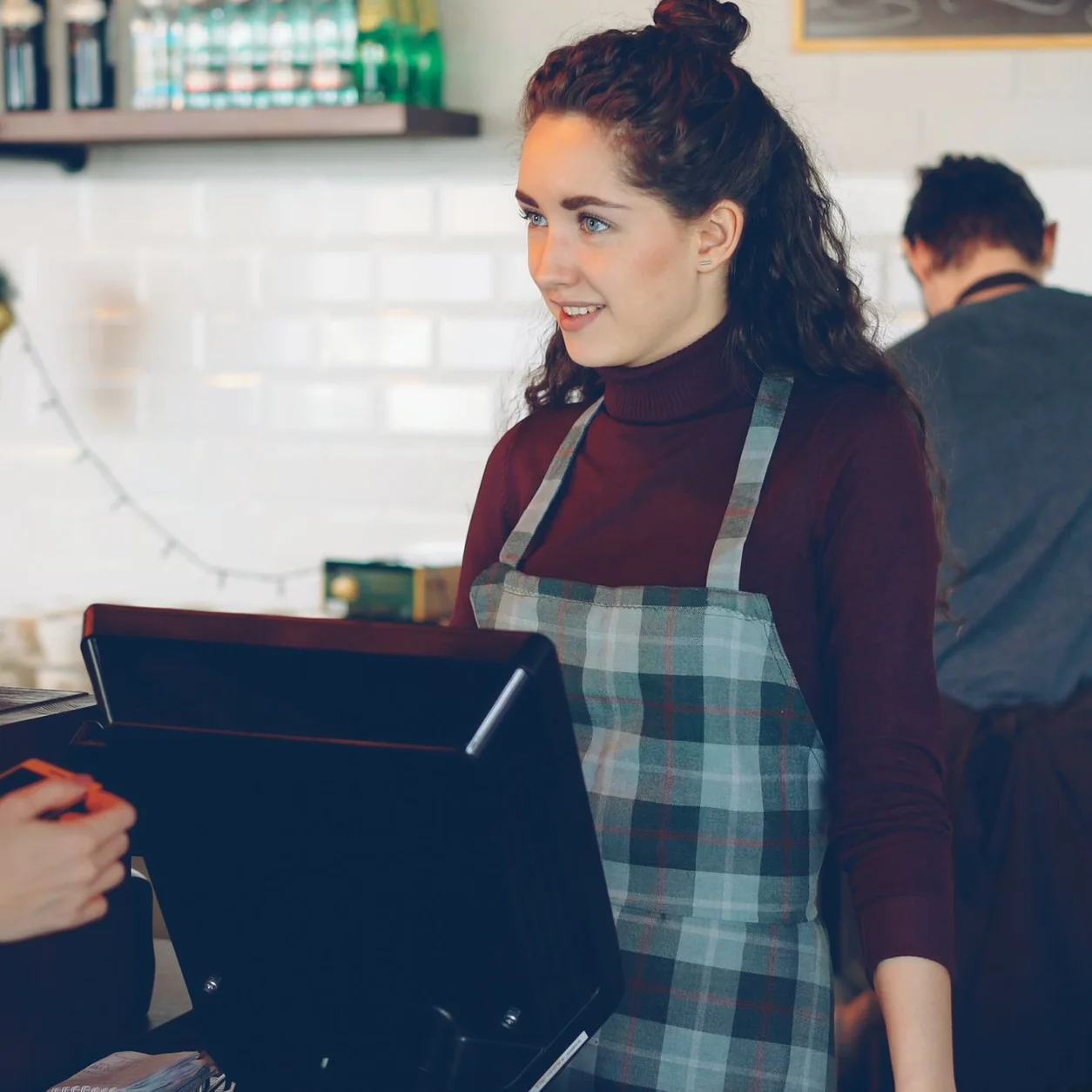 A barista helping a customer across a modern cafe counter.