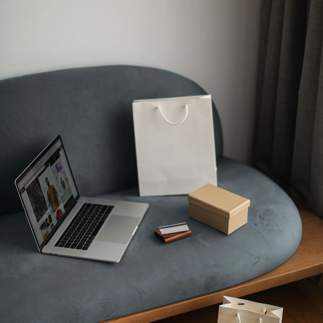 A laptop and shopping bags in a considered home setting.