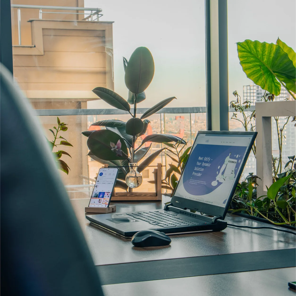 A laptop on a clean office desk beside a large window.