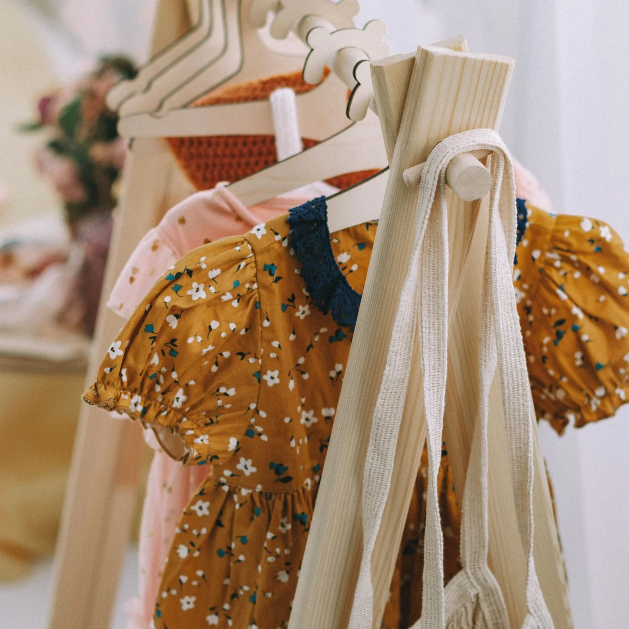 Children's dresses arranged on wooden hangers.