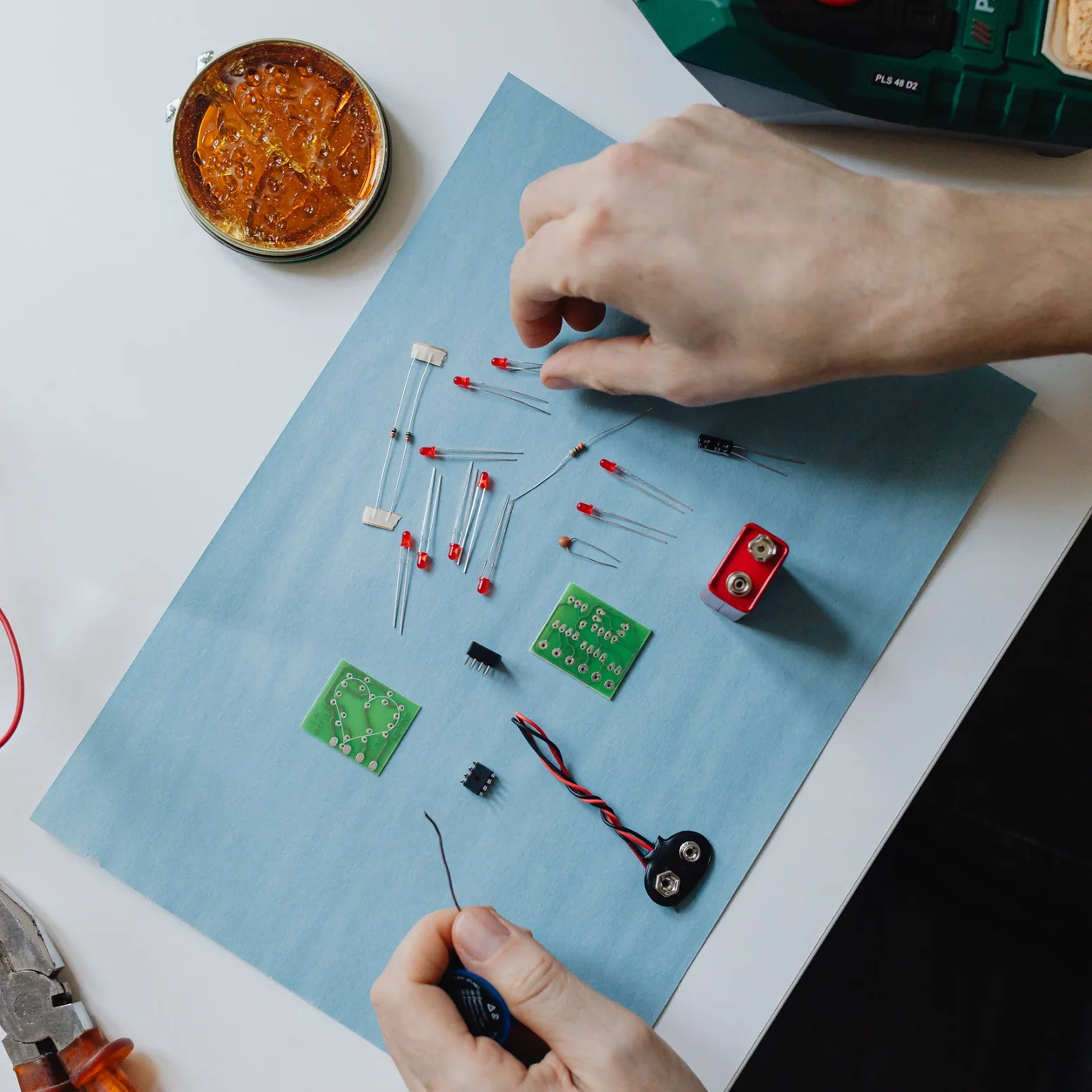 Hands working with precision tools and electronic components.