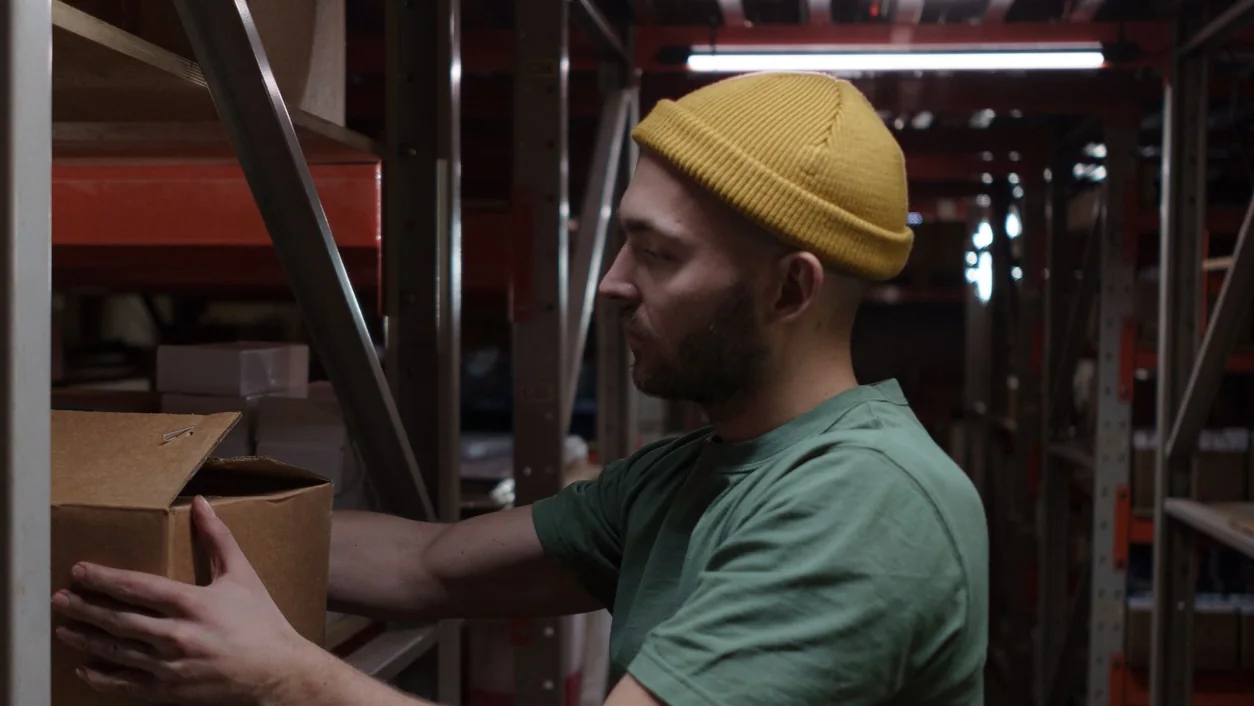 Warehouse worker organizing inventory with focus and efficiency in dim lighting.