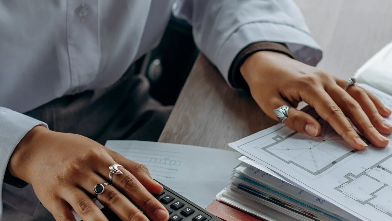 Accountant calculates finances with a calculator and documents on a desk.