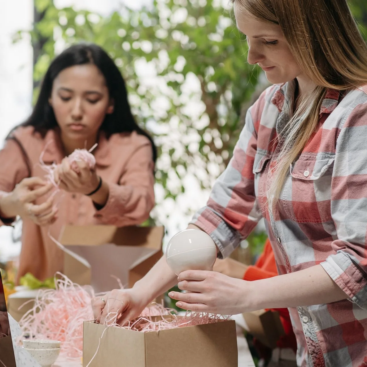 Two women packing items in cardboard boxes