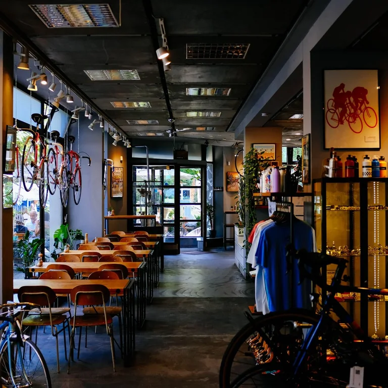 An inviting bike shop and cafe with tables, vintage bikes, and cycling accessories in a modern setting.