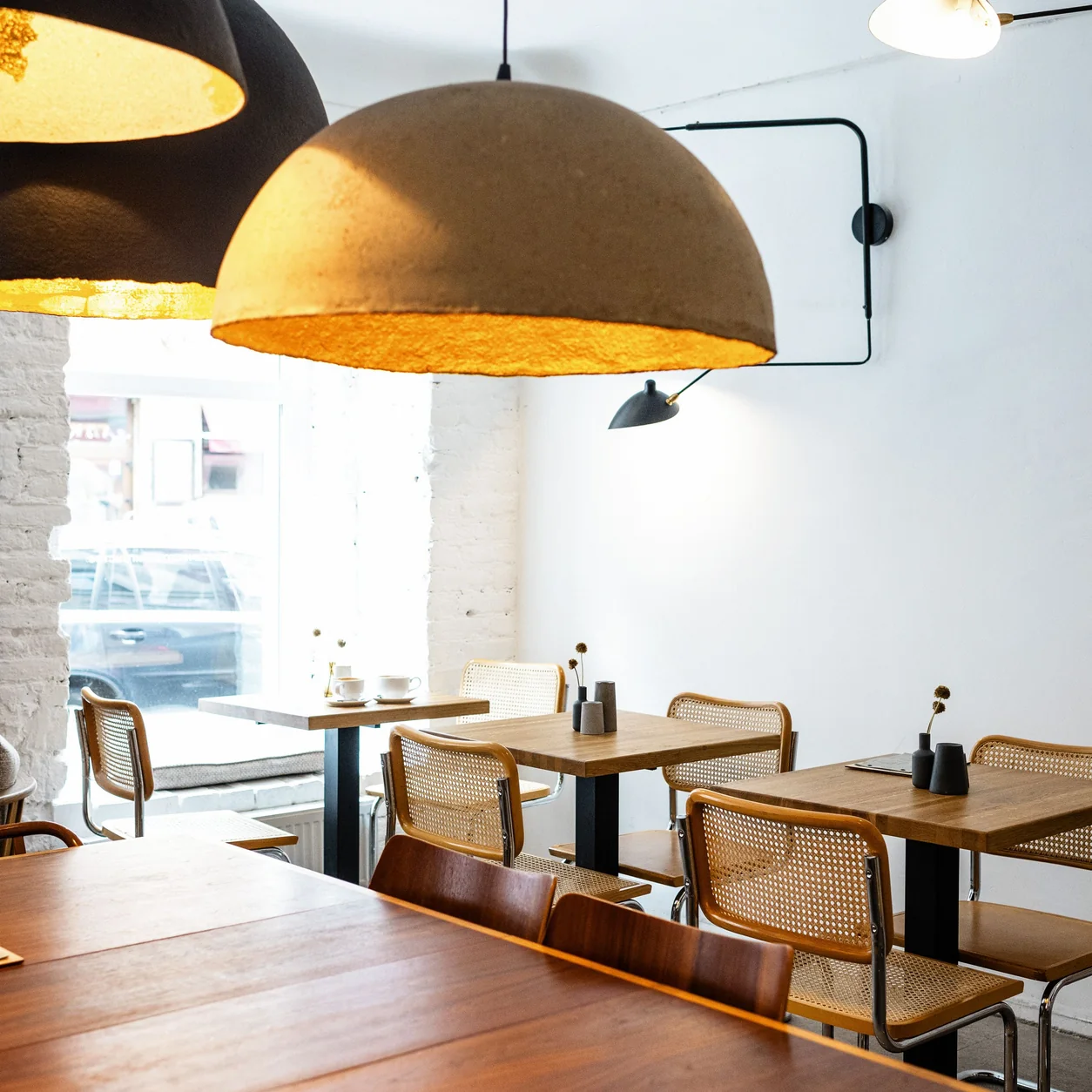 Warm pendant lighting above wooden restaurant tables.