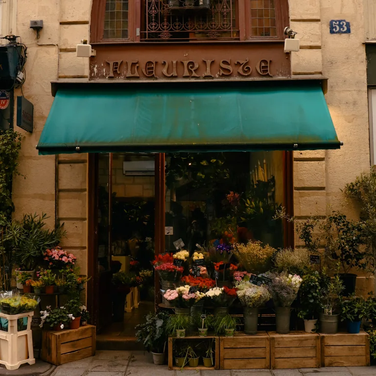 Charming Parisian flower shop with colorful blooms and vintage architecture on a sunny day.
