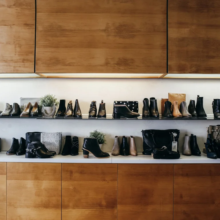 A stylish display of various shoes on wooden shelves in a modern boutique setting.