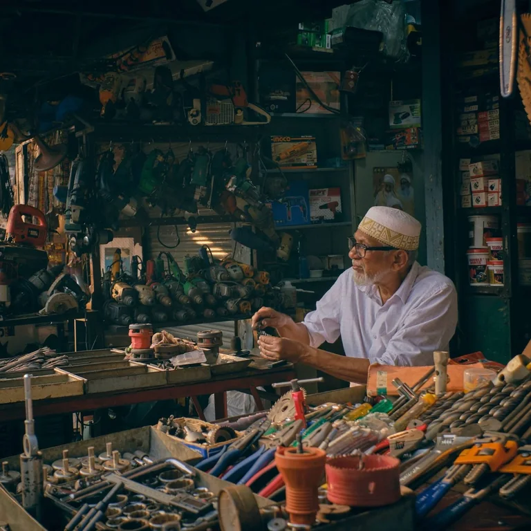 A shopkeeper sits among tools and supplies in a hardware store.