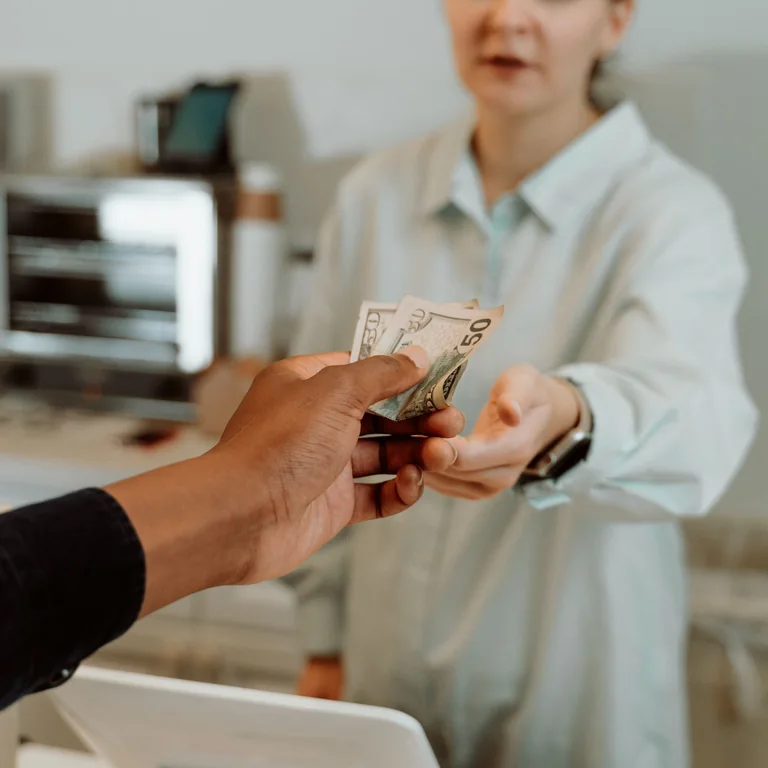 A female cashier receiving cash payment from a customer at a retail store.