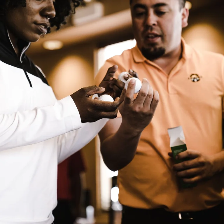A man and woman examining golf balls inside a sports store, engaging in a purchase.