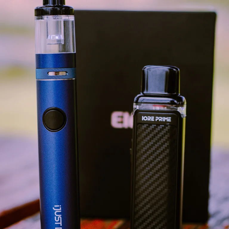 Detailed shot of blue and black vape devices on a wooden table, showcasing design and portability.
