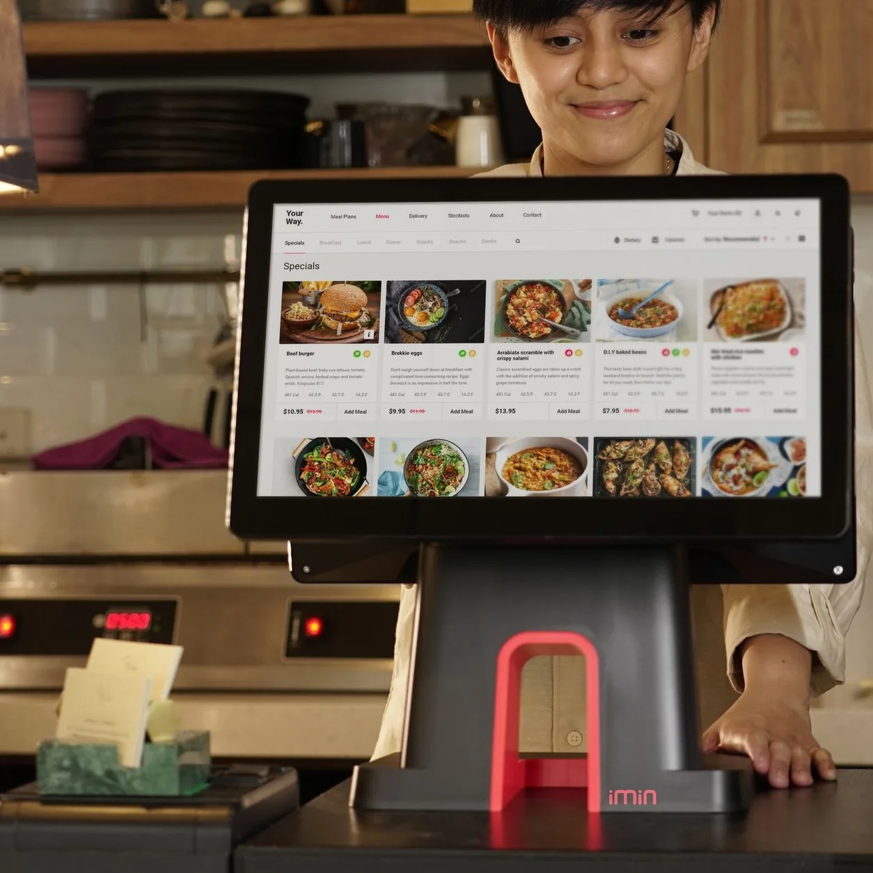 A cashier uses a touchscreen system for taking orders in a restaurant setting.