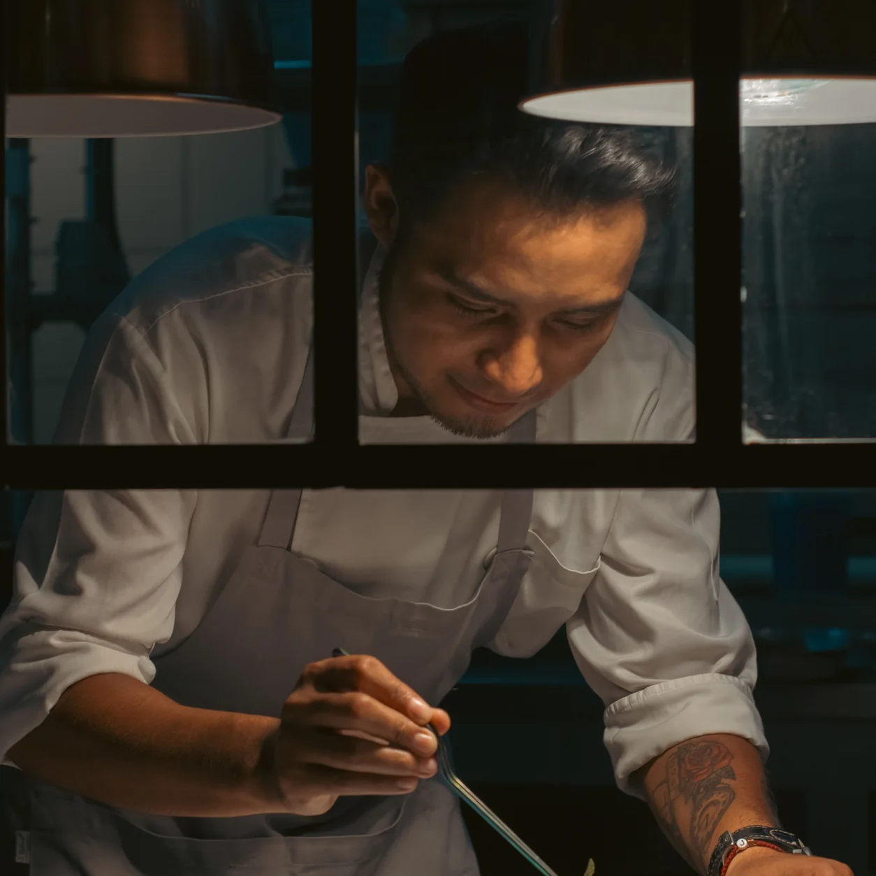A chef carefully plating a dish in a warmly lit restaurant kitchen.