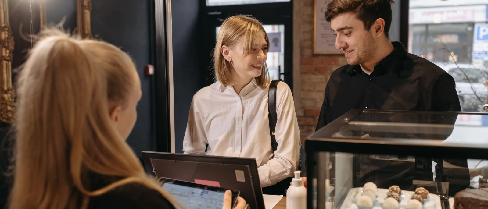 Customers interacting with a barista at a cozy coffee shop counter.
