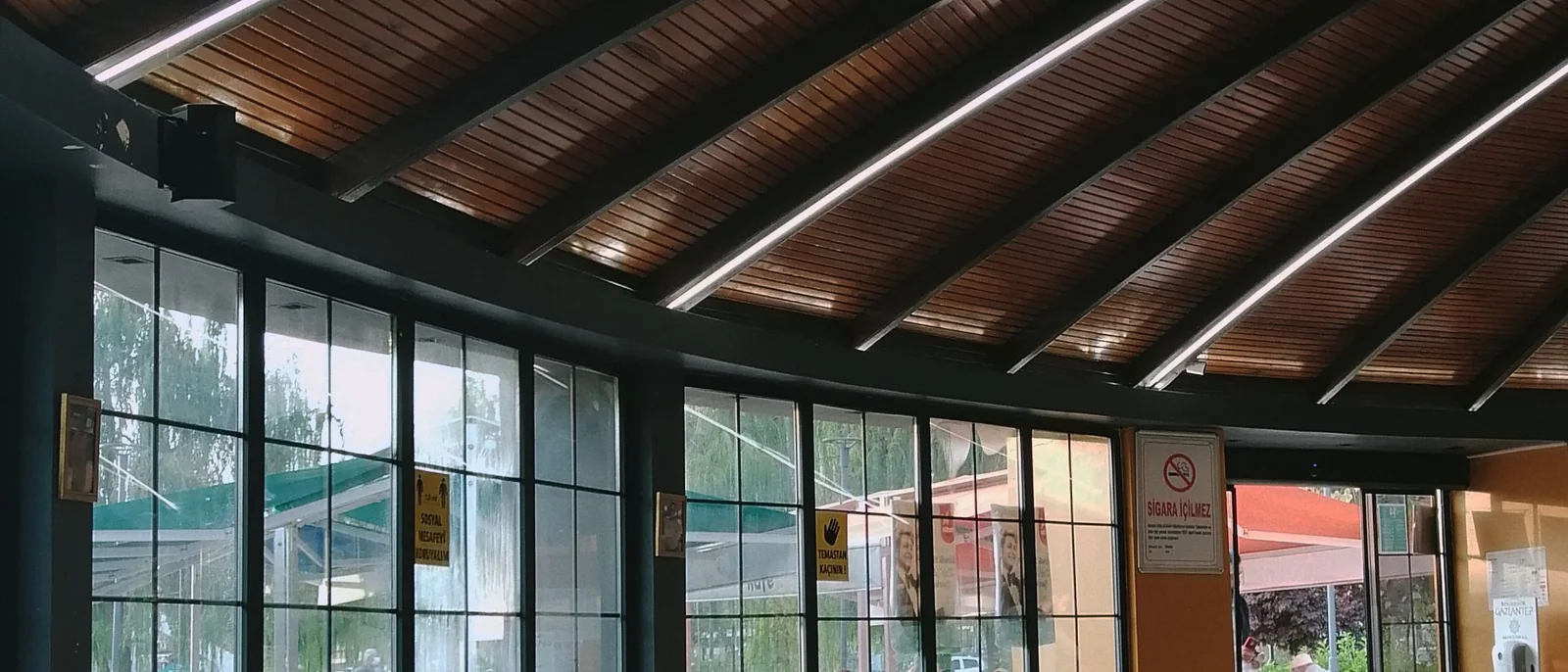 A modern restaurant interior featuring a unique wooden ceiling and stylish seating arrangements in a sunlit space.