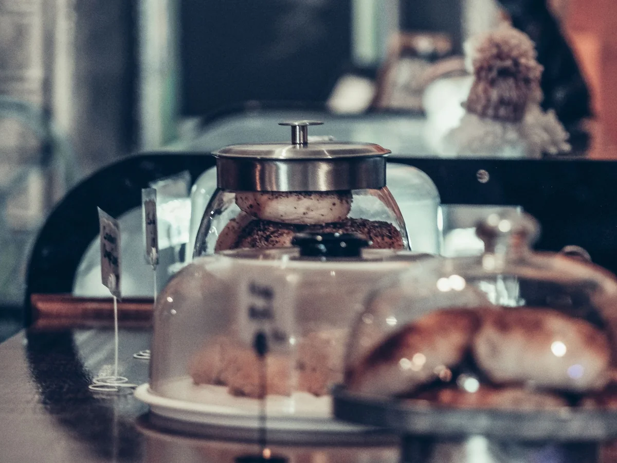 Close-up of delectable pastries under glass covers in a cozy café setting, highlighting a rustic charm.