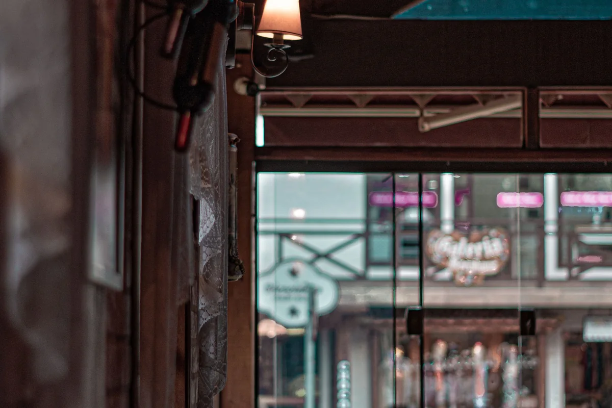 A warmly lit restaurant bar and wine display by a window.