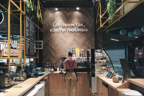 A cozy coffee shop interior with a barista preparing orders behind the counter.