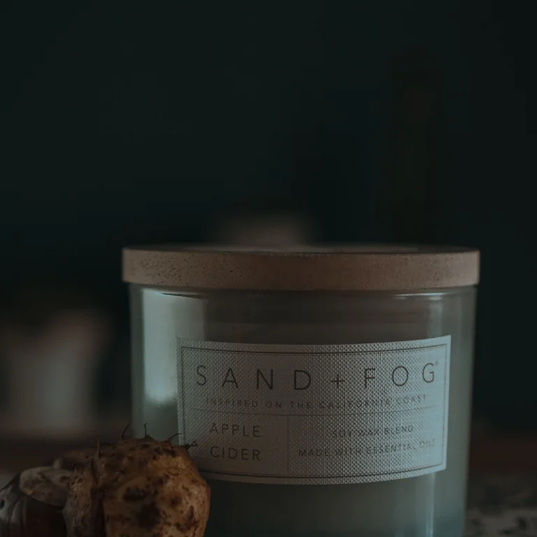 A scented candle in a glass jar beside cookies.