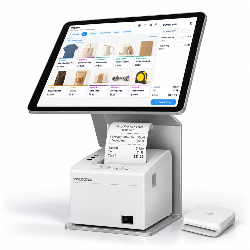 Taply Retail hardware visualization: a landscape iPad shows an everyday store catalog with clothing, groceries, home goods and gifts, above a white Volcora receipt printer with a Stripe M2 reader beside it. Demonstration data.