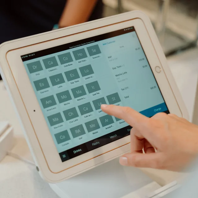 A person uses a landscape tablet on a white countertop stand.